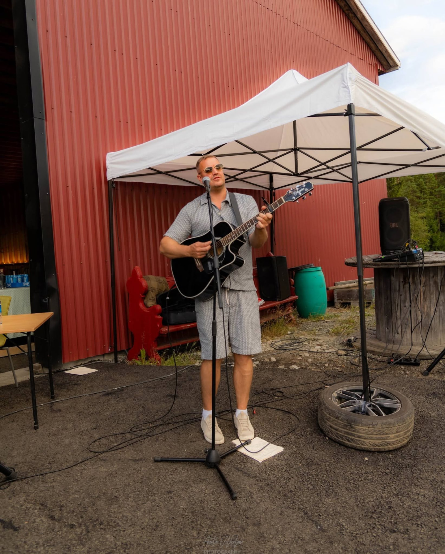 Artist spiller under telt ved låven