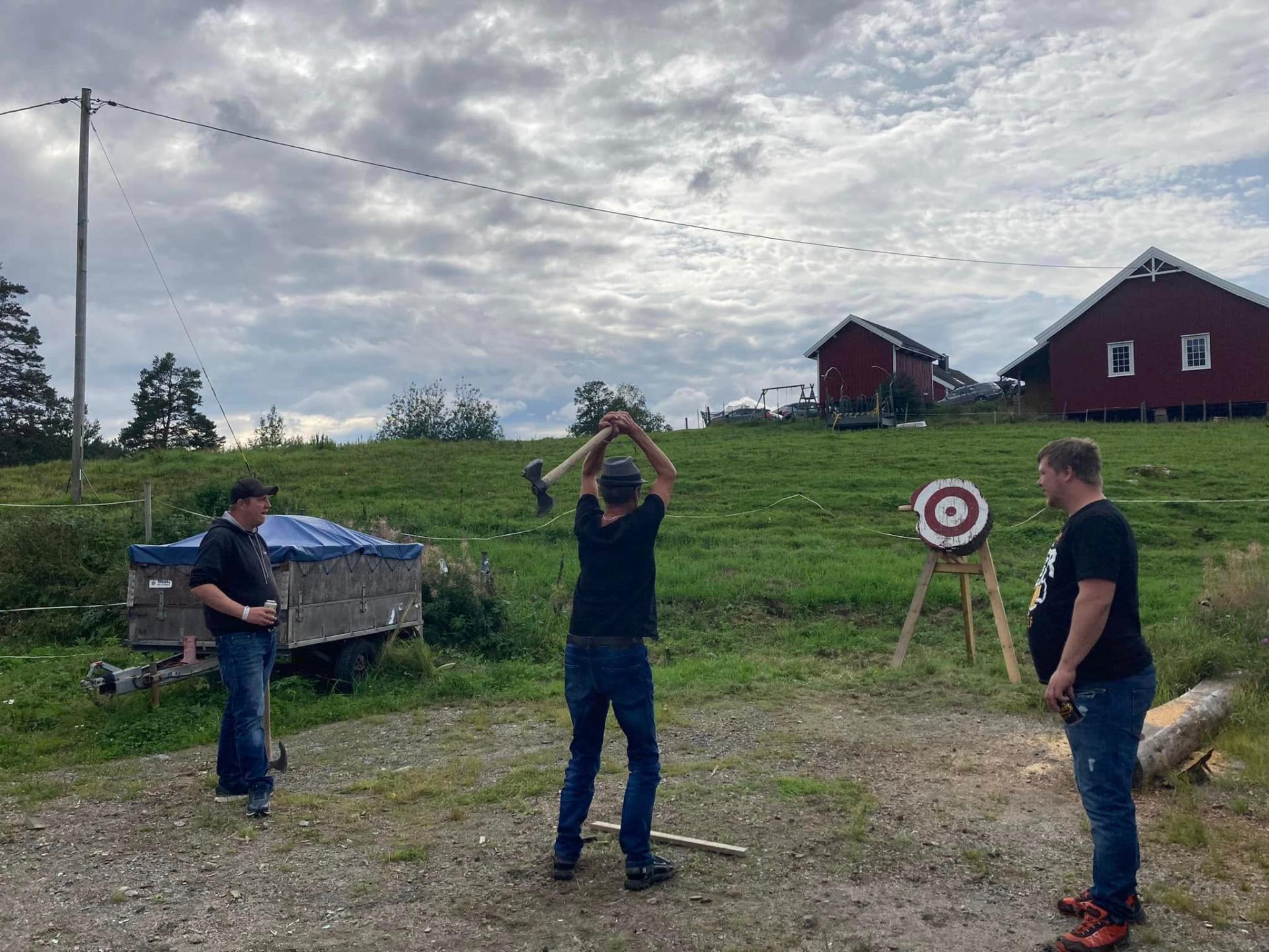 Øksekast i bakken med utsikt over låven