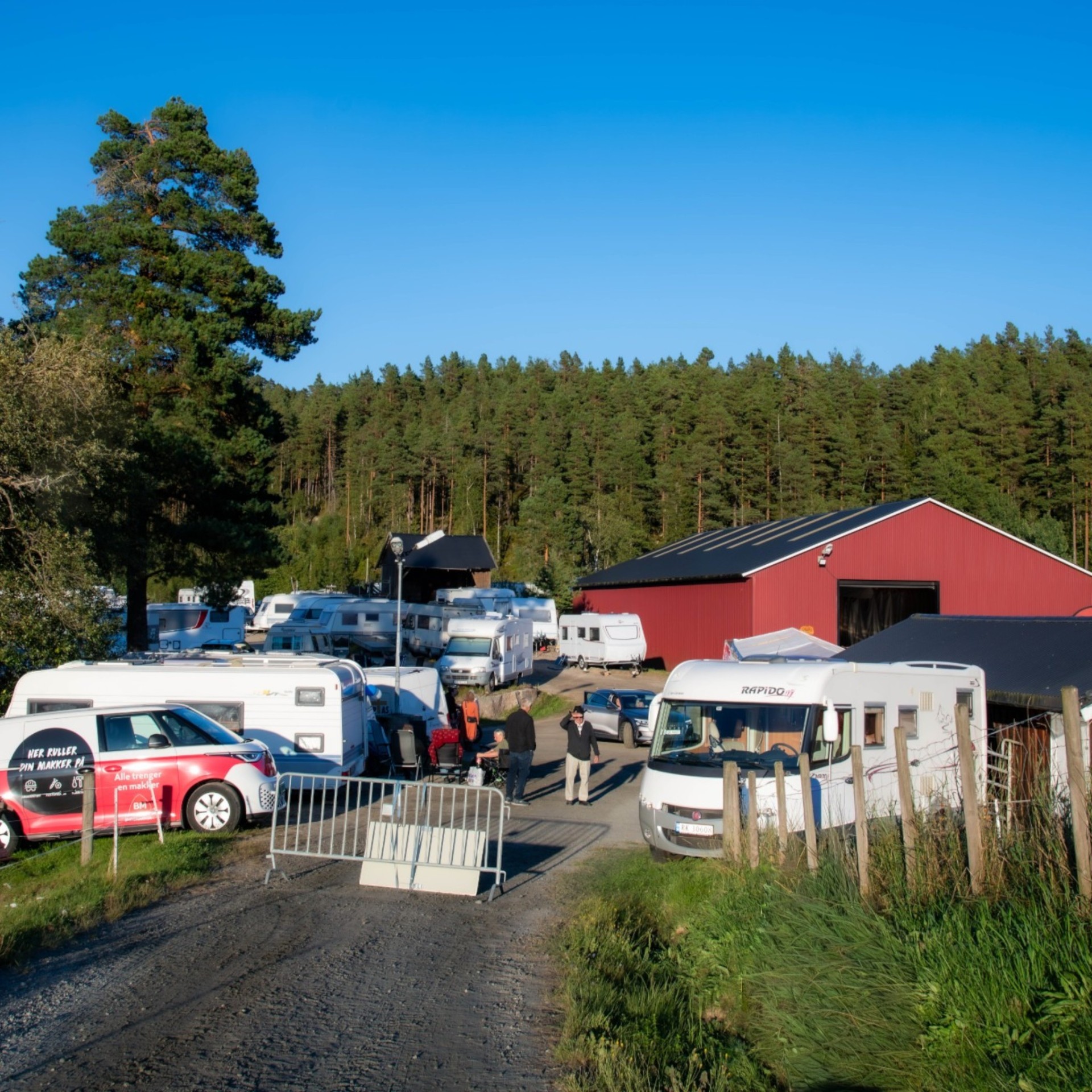 Bobiler og campingvogner samlet utenfor låven