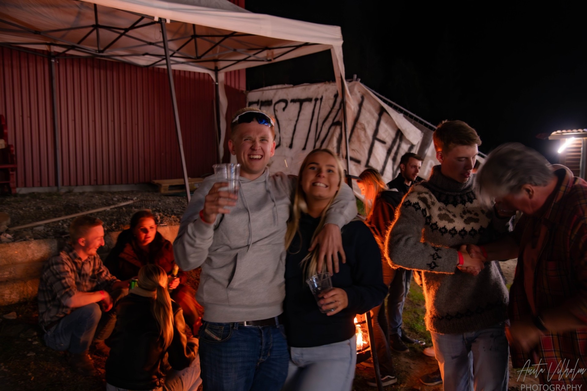 Smilende vennegjeng ved bålet på camp