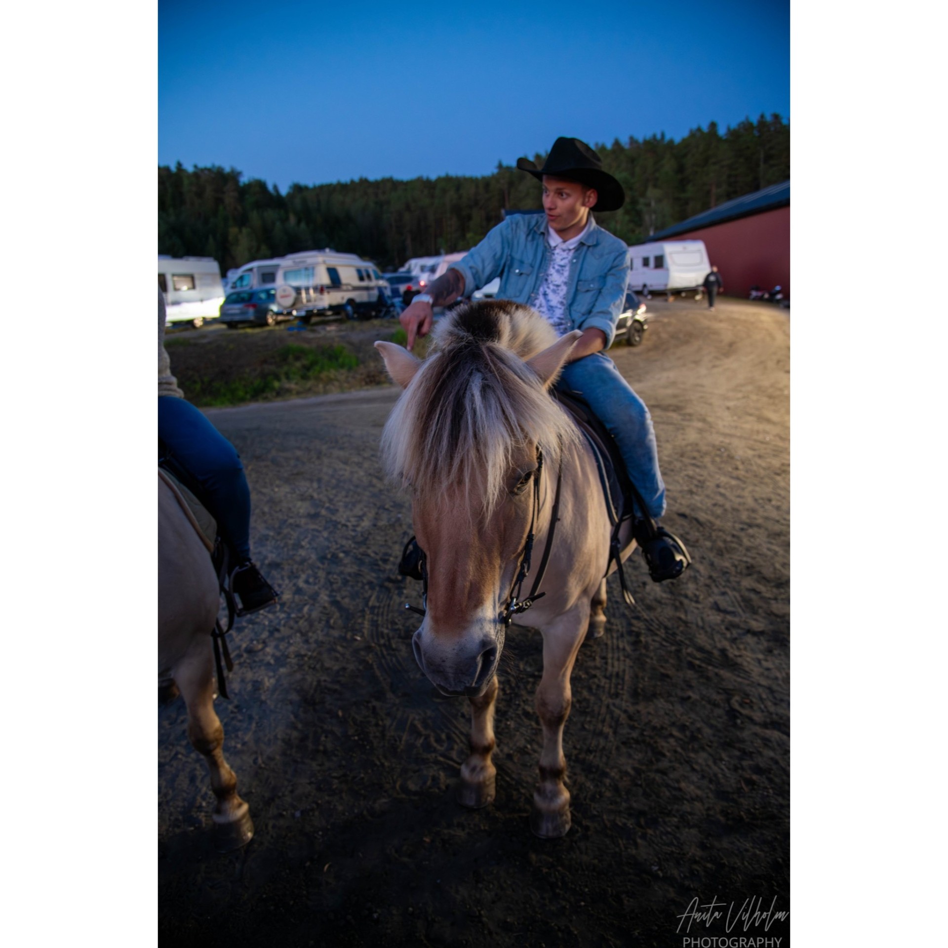 Ung cowboy rir fjordhest gjennom campen