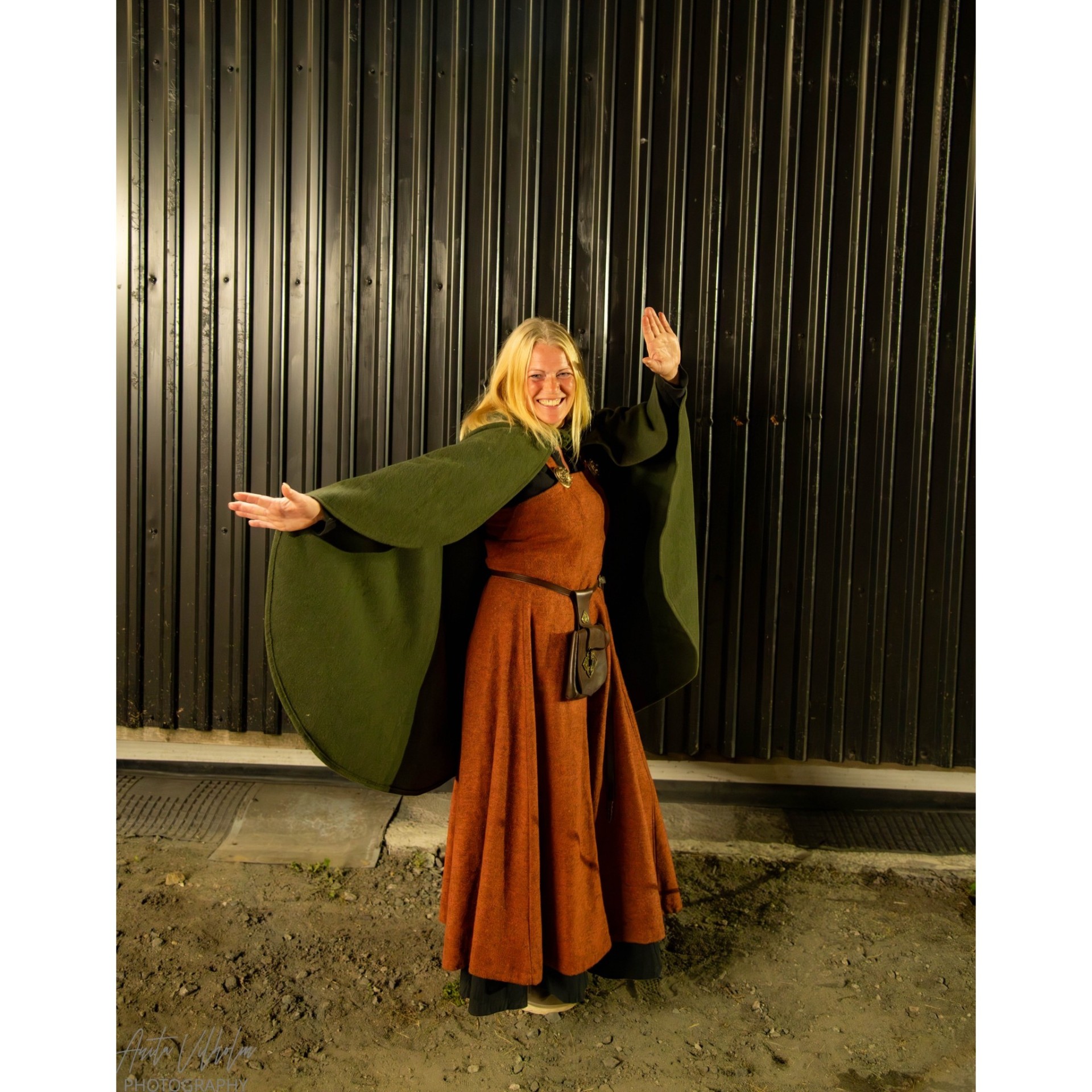 Smilende dame i vikingkappe foran låven